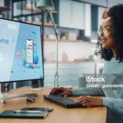 Handsome Black Female is Using Desktop Computer that Shows Welcome Page of a Popular Social Network. Freelance Woman Working Over the Internet as a Social Network Marketer.
