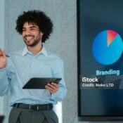 Smiling businessman giving a presentation on branding, holding a digital tablet and interacting with the audience in an office setting